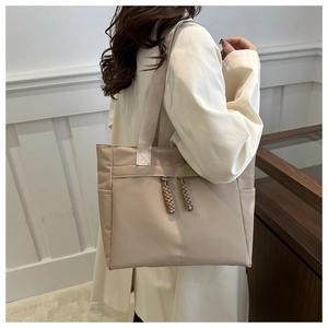 Detail view of large nylon tote bag with decorative drawstrings and wide shoulder straps