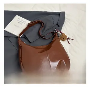 Detail view of brown PU leather hobo bag featuring contrast stitching and plush bear charm