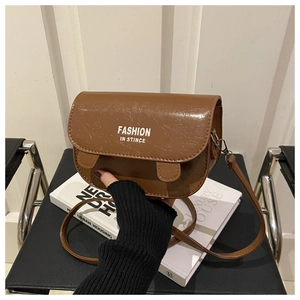 Vue détaillée de la texture du cuir ciré marron et du logo blanc sur ce sac de selle chic
