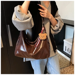 Detail of dark coffee Hobo bag in glossy leather with plush bear and rope pendant decor