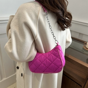 Hot pink quilted crescent shoulder bag with silver chain strap on a white coat model