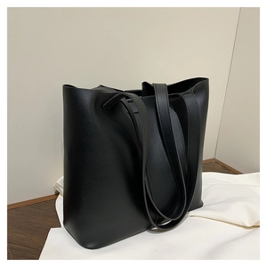 Top view of a black matte leather tote bag on white fabric with structured double straps
