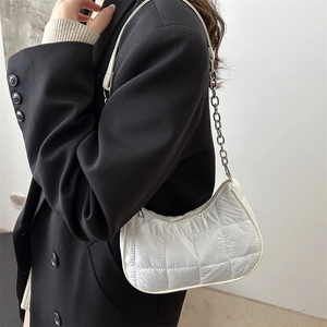Sac bandoulière blanc matelassé minimaliste avec chaîne argentée sur blazer noir