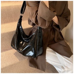 Detailed view of large black patent leather hobo bag with wide adjustable strap