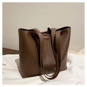 Detail view of large dark brown leather tote bag with long double handles on white fabric