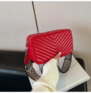 Détail du sac caméra rouge matelassé avec une large bandoulière à motifs géométriques
