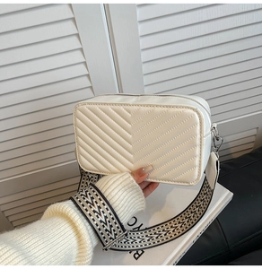 Détail du sac bandoulière blanc perle avec surpiqûres en V et large sangle jacquard