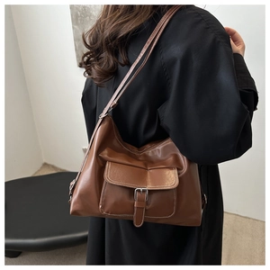 Detailed side view of brown PU leather tote bag with white stitching and silver buckle