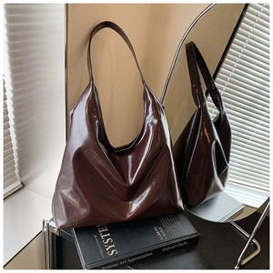 Detail of glossy deep burgundy hobo tote bag with soft leather texture and shoulder strap