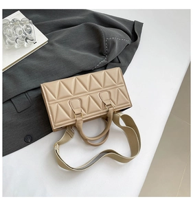Detail of beige rectangular bag with geometric triangle quilted texture and wide strap