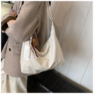 Detail of minimalist cream hobo tote with decorative knot and plush charm accessory