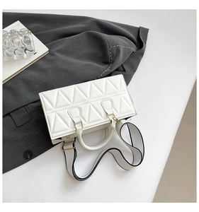 Close-up of white triangle quilted handbag with a stylish wide contrast shoulder strap