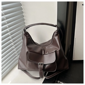 Detail of dark brown tote bag featuring contrast stitching and metal buckle pocket