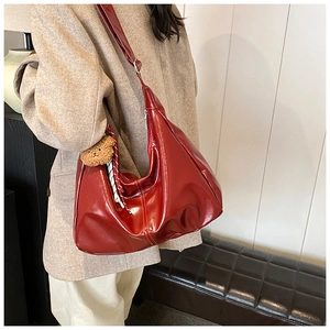 Detailed view of red patent leather hobo bag with a cute brown teddy bear keychain
