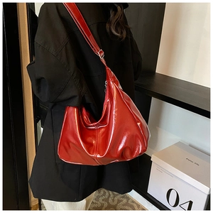 Close-up of vibrant red glossy leather tote bag with stylish shoulder strap details