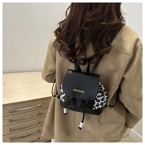 Détails du mini sac à dos avec imprimé léopard, lettrage doré et pendentif perlé