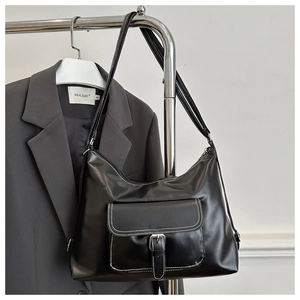 Detail of black faux leather tote with white contrast stitching and buckle pocket