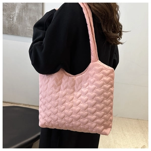 Sac cabas rose matelassé cœur porté par un mannequin pour référence de taille et style