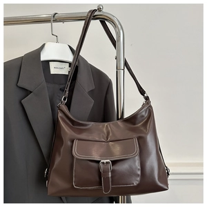Detail of dark brown tote bag featuring white contrast stitching and metal buckle pocket
