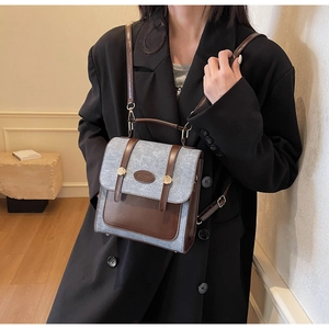 Detail of grey felt and brown leather patchwork backpack worn by a model in soft light