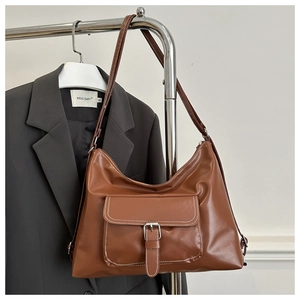 Detail of retro brown shoulder bag featuring a front pocket and metallic buckle detail