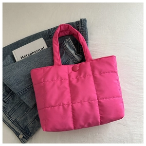 Detail of rose red quilted tote bag with checkered stitching on denim background