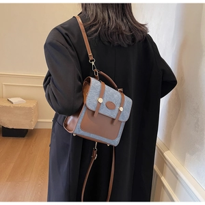 Detail of blue denim and brown leather patchwork backpack worn on a black winter coat