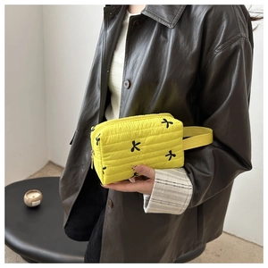 Detail of yellow quilted makeup bag with black bow embroidery and gold metal zipper