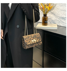 Sac bandoulière chic à motif léopard avec chaîne dorée sur une veste de blazer noire