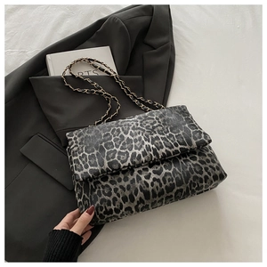 Gray leopard print shoulder bag with gold chain strap on a dark blazer background