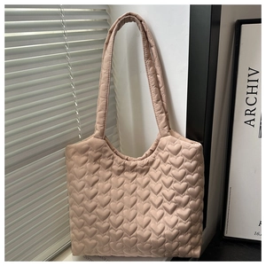 Détail du motif matelassé en forme de cœur sur sac à bandoulière souple sous lumière naturelle