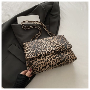 Fashionable leopard print shoulder bag with gold chain strap on white bedding