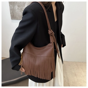 Detalle del bolso de hombro marrón con flecos con textura de lichi y correa de nudo