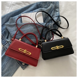 Detail of red and black mini crossbody bags with gold metal bar buckles on denim jacket