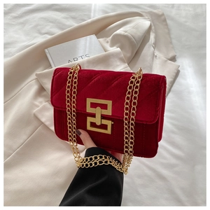Macro shot of burgundy velvet handbag with V-quilted pattern and gold geometric lock