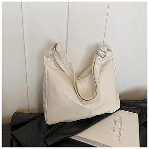 Detail of cream glossy tote bag with adjustable wide strap and silver buckle hardware