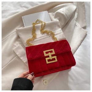 Detail of red velvet quilted crossbody bag featuring elegant gold chain strap and metal lock