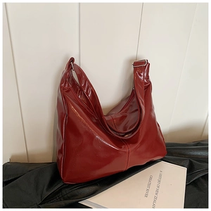 Detail of burgundy glossy patent leather hobo bag with adjustable buckle on black leather