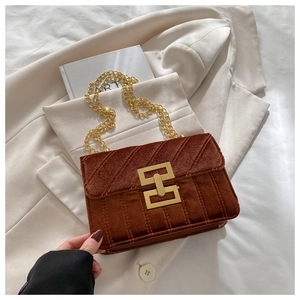 Close-up of velvet quilted texture and golden chain strap on stylish shoulder bag