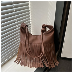 Detalle de bolso hobo de cuero granulado marrón con flecos largos y correa con nudos