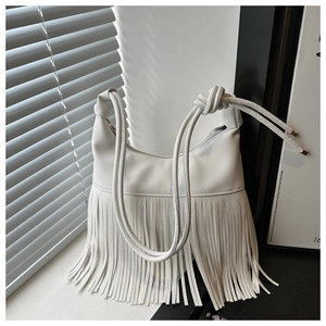 Detalle de bolso bandolera de cuero lichi blanco con flecos largos y sombras artísticas