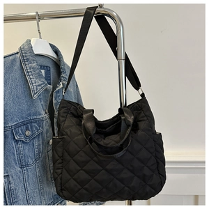 Detail of black quilted tote bag with diamond pattern and adjustable shoulder strap