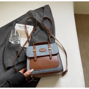 Detailed view of mixed denim and leather backpack placed on elegant white bedding