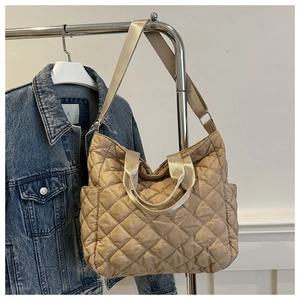 Close-up of beige quilted tote bag with diamond pattern and adjustable shoulder strap