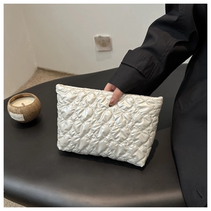 Détail d'une pochette blanc nacré avec matelassage en cœur et fermeture éclair fluide
