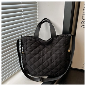 Detailed side view of black quilted tote bag featuring side pockets and adjustable strap