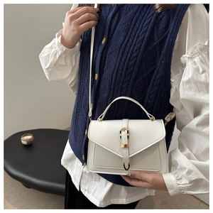 Détail du sac à main blanc minimaliste avec boucle dorée porté par un mannequin