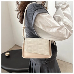Detail of beige shoulder bag featuring woven texture flap and decorative knot strap