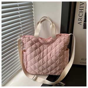 Close-up of light pink quilted tote bag showing embroidered stitching and shoulder strap