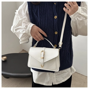 Détail du petit sac blanc minimaliste porté avec un pull sans manches en maille bleue